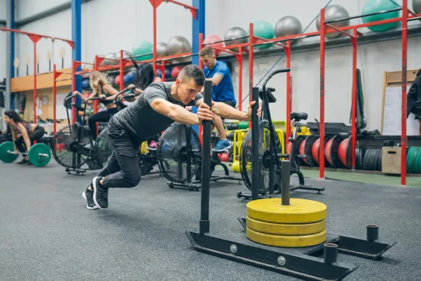 Atleta empujando un trineo cargado con discos durante un entrenamiento funcional de preparación para HYROX